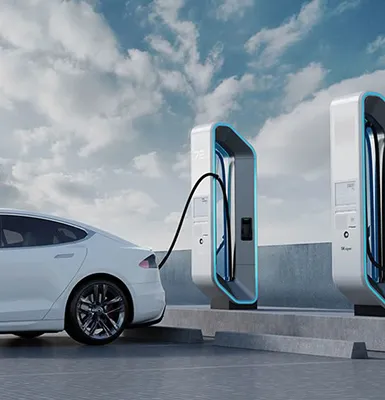 A white electric vehicle parked under a solar-powered canopy charging station, with solar panels on the roof.