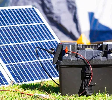 Technician working on wiring for ground-mounted solar panels outdoors.