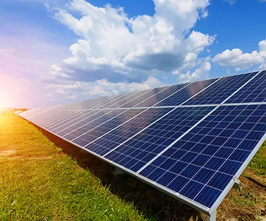 Solar panels on a field under a blue sky with scattered clouds, illustrating clean and sustainable solar energy benefits.