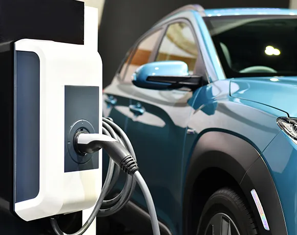 Blue electric SUV plugged into a Level 2 home EV charging station.