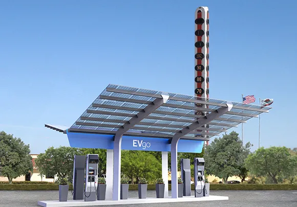 Commercial EV charging station with solar panel canopy and industrial buildings in the background.