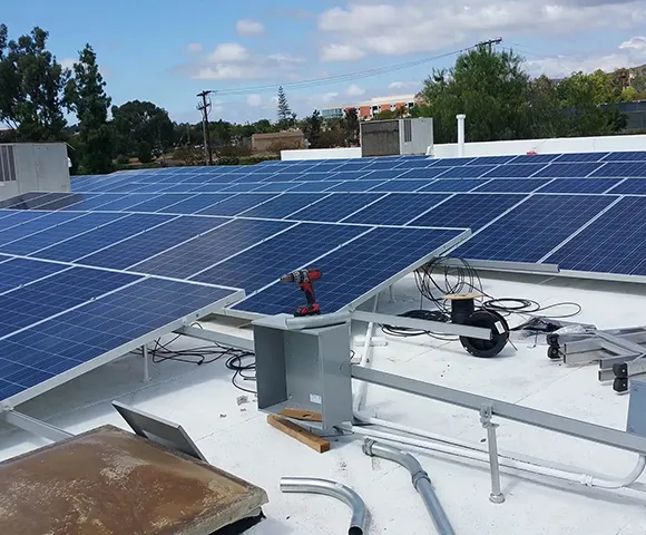 Large rooftop commercial solar panel array installed under clear sky.