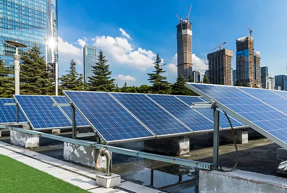 Ground-mounted solar panel arrays with a city skyline in the background.