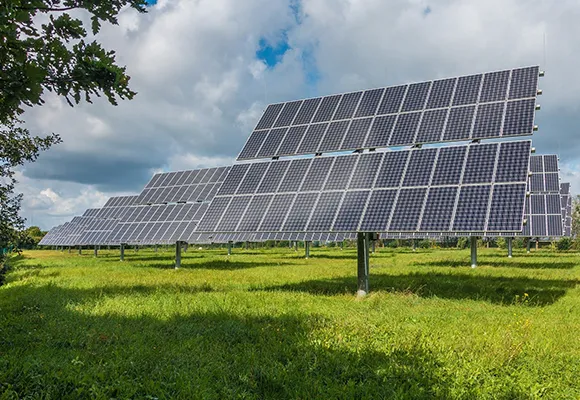 Solar panel array installed on a grassy field under a partly cloudy sky, representing custom payment plans for solar systems in Fort Myers, FL.