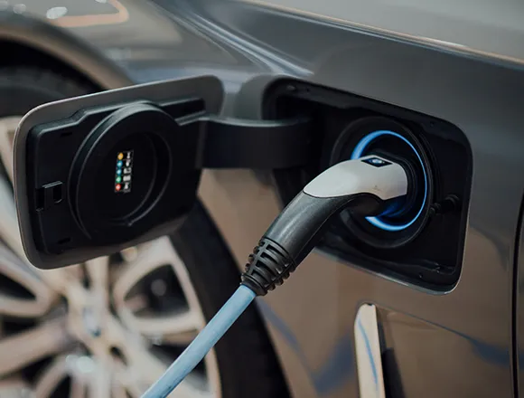 A close-up of an electric vehicle charging station with a cable connected to a car.