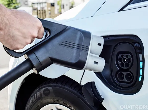 Hand plugging Level 2 EV charger into electric vehicle charging port.