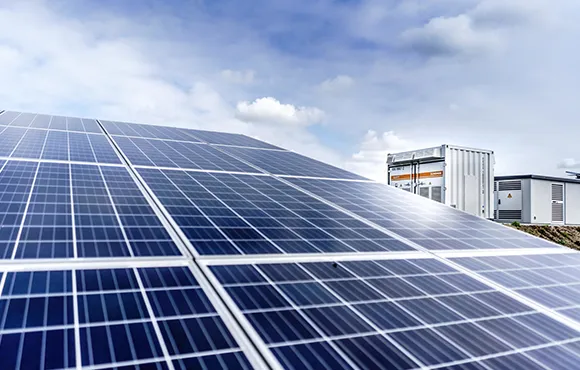 Close-up view of rooftop solar panels against a blue sky with buildings.