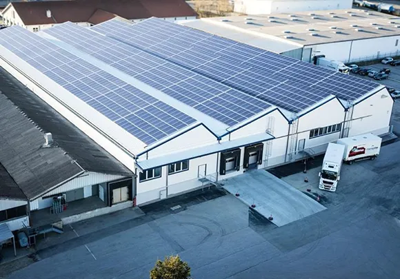Solar panels installed on a large industrial warehouse rooftop.